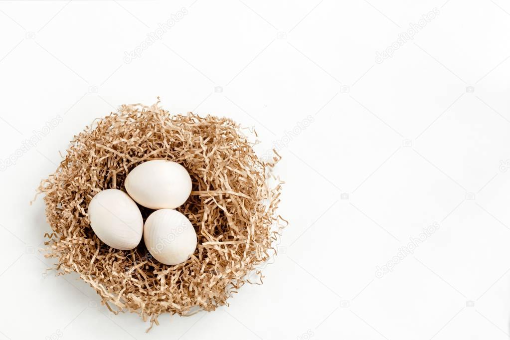 Wooden eggs in the nest on white background.