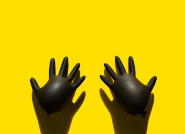 Sarı arka planda iki şişirilmiş siyah lateks eldiven. Pop sanat tarzı.