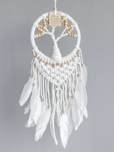 Dreamcatcher, an American native amulet made of feathers, leather beads, and ropes with the symbol of a tree and instruction card.