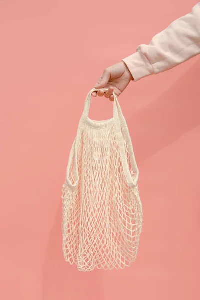 一个女人的手拿着一个空的可重复使用的购物袋 粉色背景 生态习惯 — 图库照片
