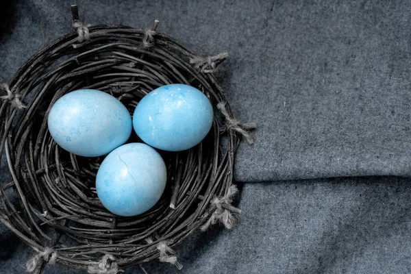 Gri kumaş arka planda bir yuvadaki Paskalya renkli yumurtalar