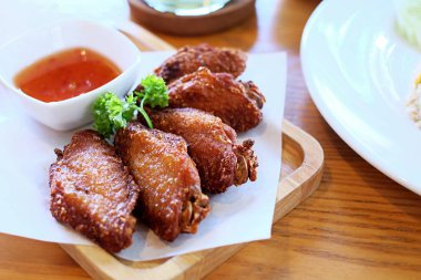 Ahşap plaka üzerinde kırmızı soslu kızarmış tavuk.