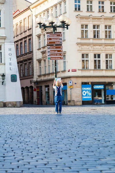 Hermosa joven en Praga mira el mapa de la ciudad . — Foto de Stock