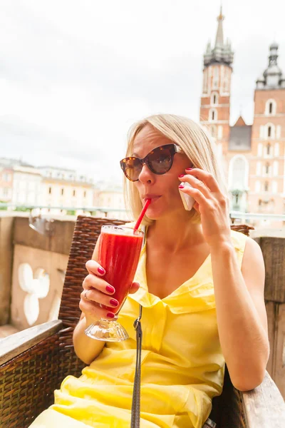 Жінка п'є коктейль і говорити по телефону перед St Marys костелу у Кракові. Польща. — стокове фото