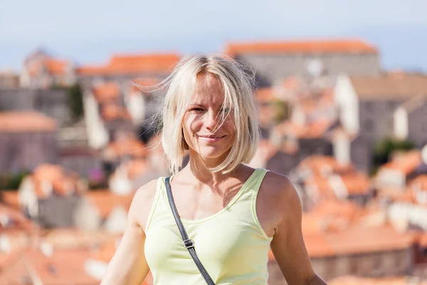 Beautiful young blonde girl on a background of blurred panoramic cityscape. Dubrovnik — Stock Photo, Image