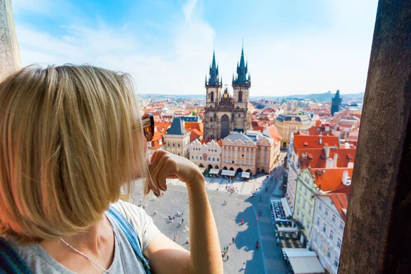Young woman stands on top of clock tower and looks at Old Town Square in Prague — Stock Photo, Image