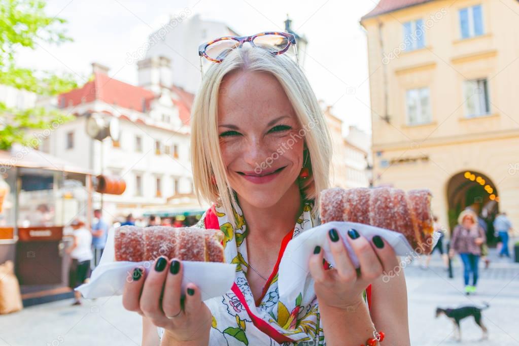 Young female tourist with traditional czech dessert called trdelnik. Prague