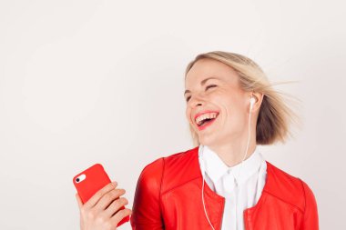 Kulaklıklar ve beyaz zemin üzerine kırmızı ceketli elinde cep telefonu ile bir kadın portresi