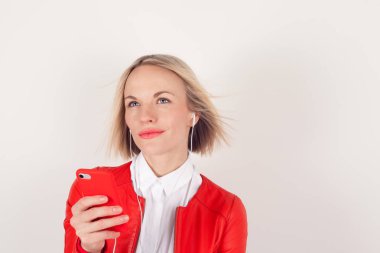 Kulaklıklar ve beyaz zemin üzerine kırmızı ceketli elinde cep telefonu ile bir kadın portresi