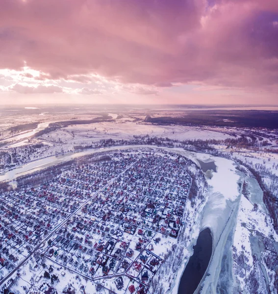 Bir nehir ve kışın gün batımında alanları yanında Suburban'ı şehrin havadan görünümü.