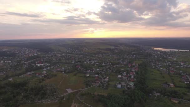 Veduta aerea della città suburbana vicino a un fiume e campi al tramonto in estate — Video Stock