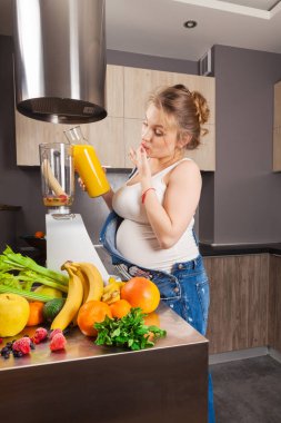 Hamile kadın kendini ve çocuğunu mutfak için bir meyve güler yüzlü yapar