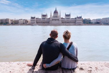 İki kişi Rıhtımlar üzerinde oturmak ve Budapeşte, Meclis'te manzarasının keyfini çıkarın