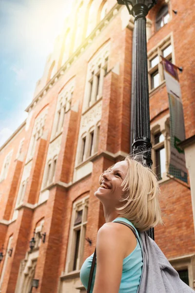 Mladá krásná žena na ulici podél staré cihlové budovy na pozadí slunečního záření — Stock fotografie
