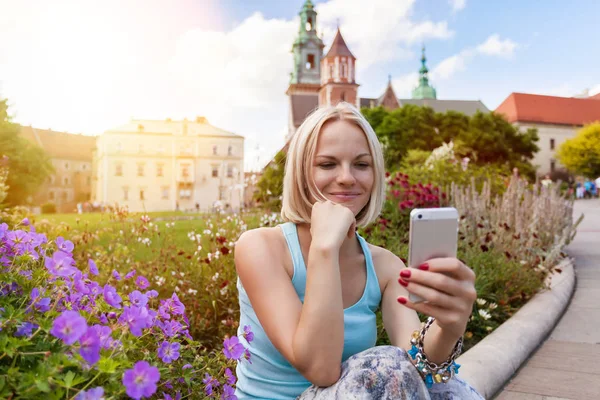女性旅行者坐着看手机上的瓦维尔城堡背景中 — 图库照片