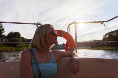 Bir kadın Nehri üzerinde tekne ile günbatımında yelken açtı