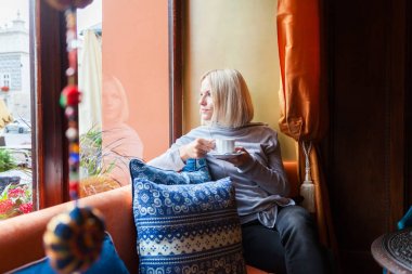 Bir kadın bir kafede dinlenme ve pencerenin dışındaki manzarayı.