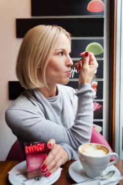 Genç kadın sabah kruvasan ve hafif köpük tatlı kahve içer