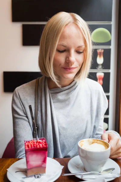 Genç kadın sabah kruvasan ve hafif köpük tatlı kahve içer