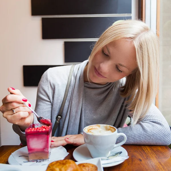 Genç kadın sabah kruvasan ve hafif köpük tatlı kahve içer