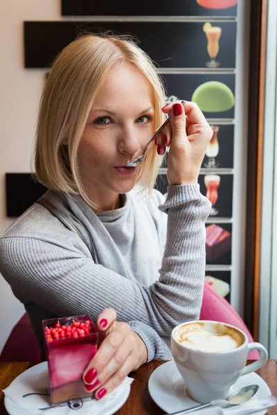 Genç kadın sabah kruvasan ve hafif köpük tatlı kahve içer