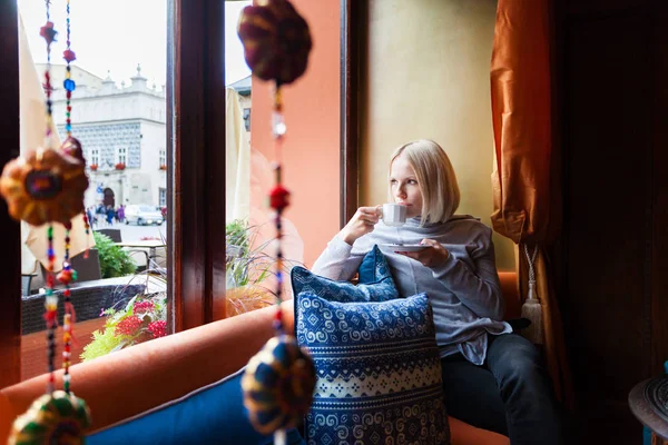 Una donna si riposa in un caffè e gode la vista fuori dalla finestra . — Foto Stock