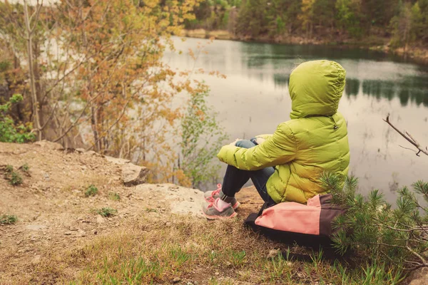 Mladá dívka bokovky s batohem se kochat výhledem na jezero. — Stock fotografie