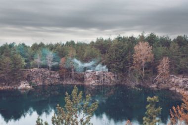 View of the lake below the rocks in the middle of a pine forest clipart