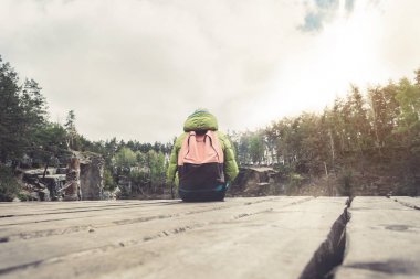 Kadın bir gezgin ahşap bir iskele çam ormanları güzel bir göl yakınında oturuyor.