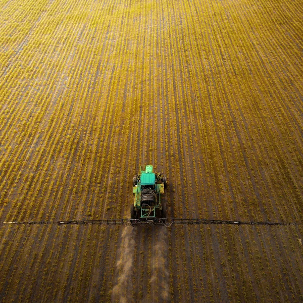 The tractor spraying the field with chemicals in the spring — Stock Photo, Image