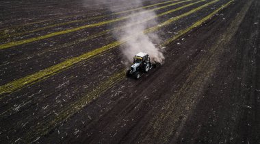 Tractor cultivating field at spring, aerial view clipart