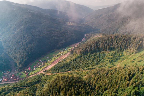 Aerial view of the village in the Carpathian mountains with clouds in the foreground — Stock Photo, Image