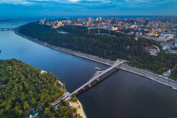 Kiev şehir merkezi panoramik manzaralı. Kiev Dinyeper Nehri, bir yaya köprüsü ve gün batımında geniş park alanı ile değil bankanın havadan görünümü. — Stok fotoğraf
