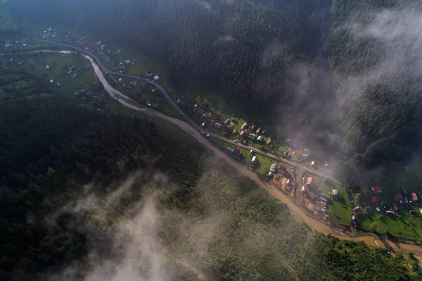 Vista aérea da aldeia nas montanhas dos Cárpatos com nuvens em primeiro plano — Fotografia de Stock