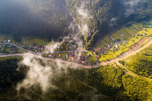 Vista aérea da aldeia nas montanhas dos Cárpatos com nuvens em primeiro plano — Fotografia de Stock