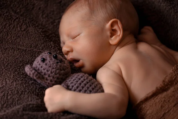 Neugeborenes schläft in einer schönen Pose mit einem kleinen Bären — Stockfoto