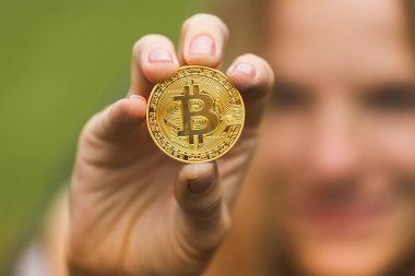 Bir kadın bir altın sikke bitcoin elinde tutar.