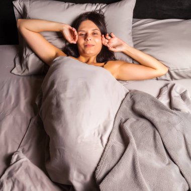 Yatakta ve streç kendini karanlık bir arka plan üzerinde uyuyan kadın.