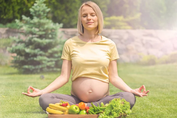 Pregnant woman practicing meditation and relaxation in nature
