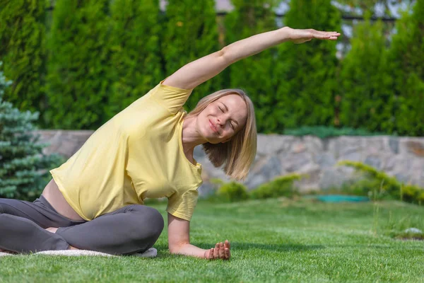 Hermosa mujer embarazada haciendo yoga prenatal en la naturaleza . — Foto de Stock