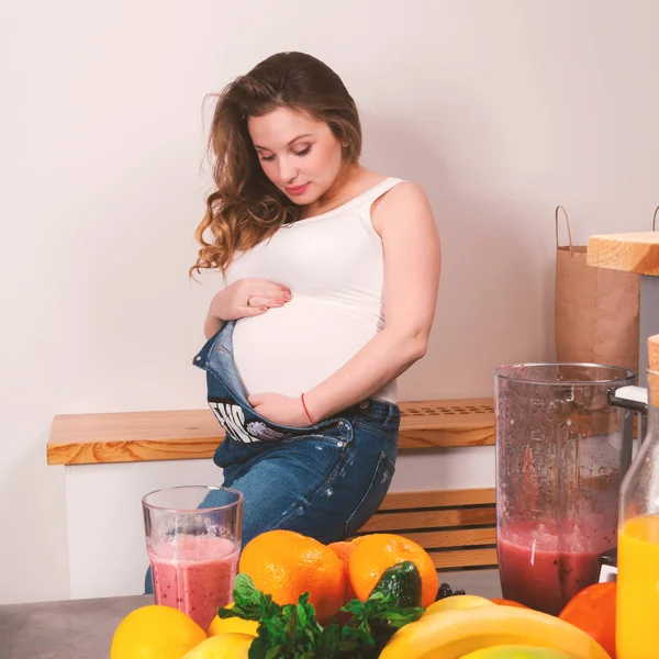 Красивая беременная женщина гладит живот фруктами на переднем плане — стоковое фото