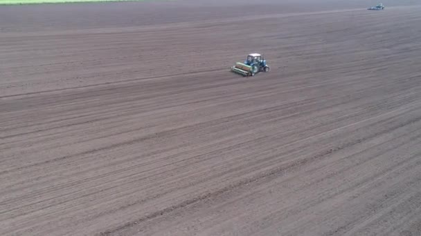 Circulaire vlucht luchtfoto van twee tractoren rijden achter elkaar in het veld — Stockvideo