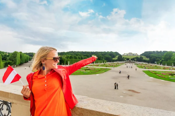 Ung kvinnlig turist med Österrikes flagga står mot Schönbrunns slottspark i Wien, Österrike — Stockfoto