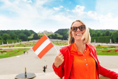 Avusturya bayrağı taşıyan genç bayan turist Avusturya, Viyana 'da bir Schoenbrunn saray parkına karşı duruyor.