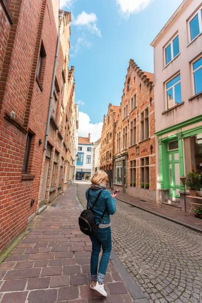 Mujer turista perdida en las calles de la ciudad y está buscando en su teléfono cómo llegar más lejos, Brujas, Bélgica — Foto de Stock