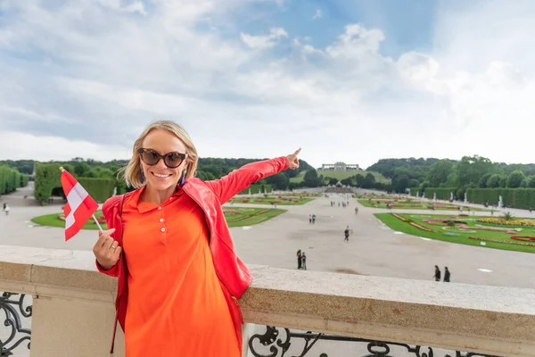 Ung kvinnlig turist med Österrikes flagga står mot Schönbrunns slottspark i Wien, Österrike — Stockfoto