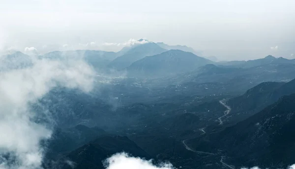 Panorama of beautiful silhouette mountains in blue tones with haze and clouds. — Stock Photo, Image