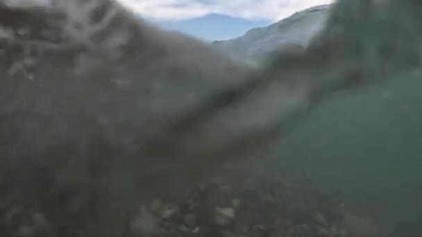 Узбережжя з кам'яним пляжем і повільним рухом морської хвилі з зануренням камери під воду . — стокове відео