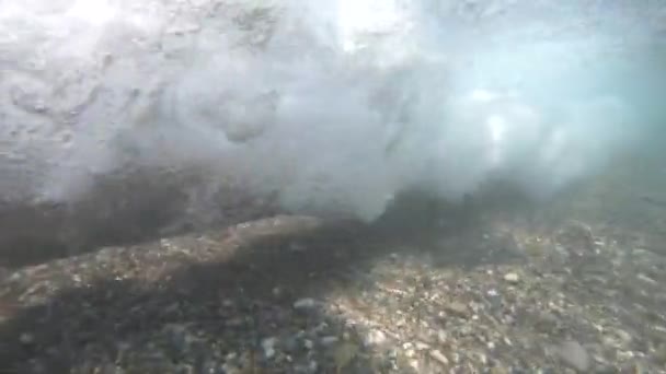 Die Küste mit einem Steinstrand und Zeitlupe der Meereswelle mit dem Untertauchen der Kamera unter Wasser. — Stockvideo