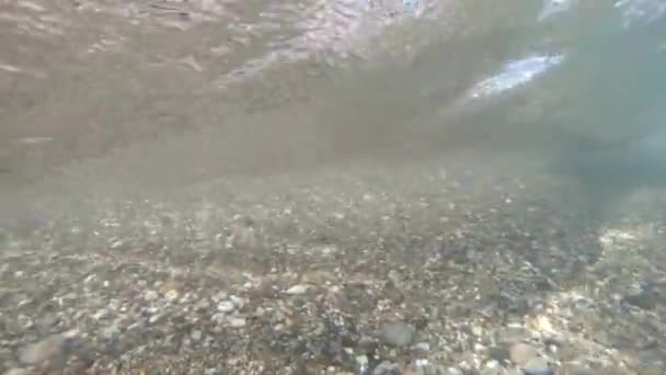 Sahili taştan bir sahil ve kameranın suyun altına dalmasıyla deniz dalgasının yavaş çekimi.. — Stok video